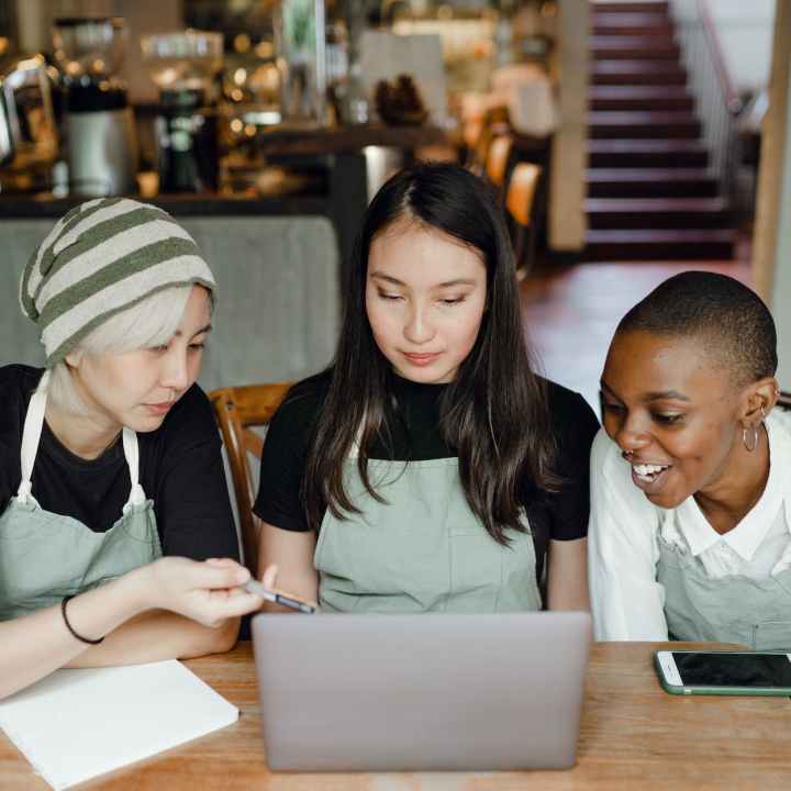 happy waitresses watching tutorials on laptop
